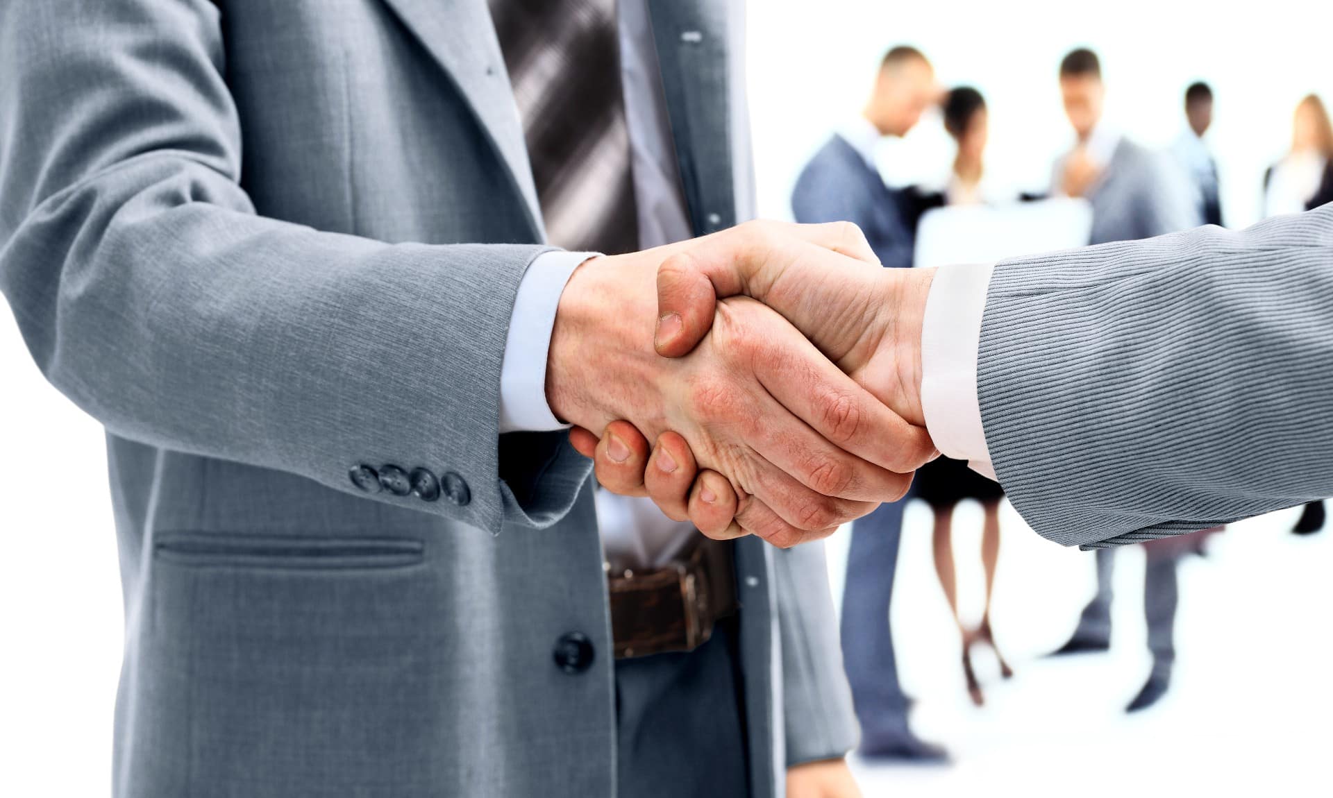 businessmen-shaking-hands-with-team-behind