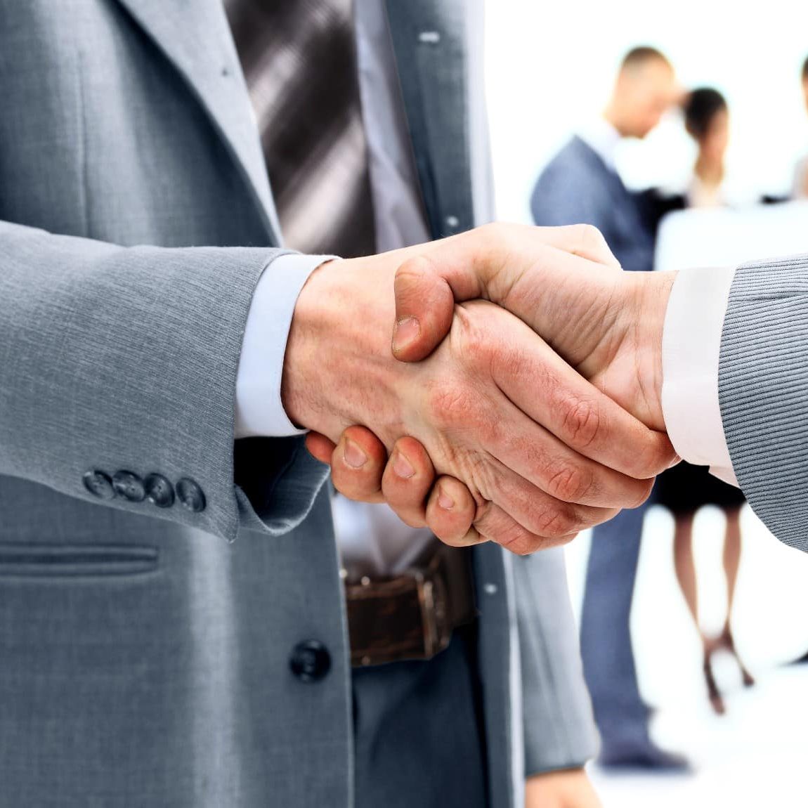 businessmen-shaking-hands-with-team-behind